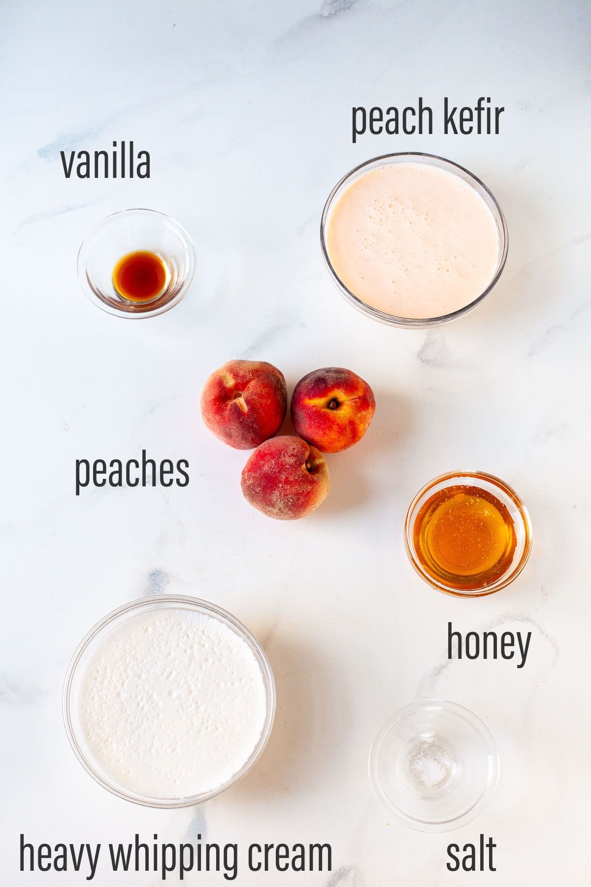 ingredients for peach kefir ice cream in glass bowls on marble surface with text overlay